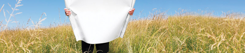 Photo - person in field holding blueprint